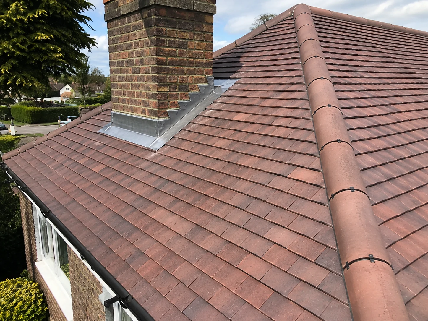 Tiled roof detail showing chimney flashing, ridge tiles and gutter